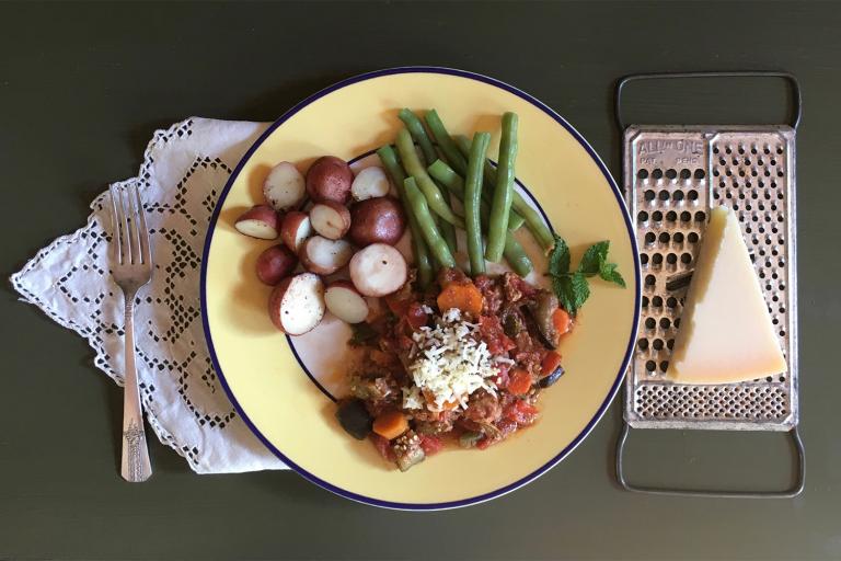 a plate of ground turkey cooked with vegetables, with potatoes and green beans