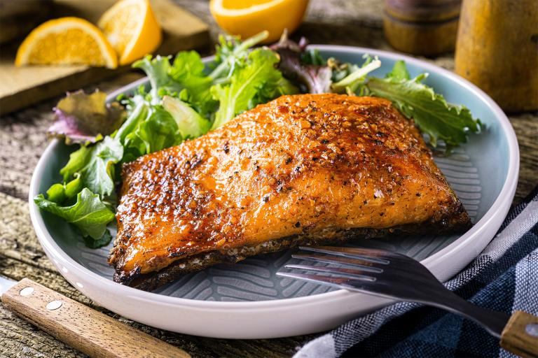 pan-seared salmon served with lemons over a mix of greens
